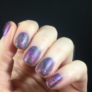 Left hand fingers and thumb curled towards the camera on a black background with grey nails and purple-pink gradient stamped design
