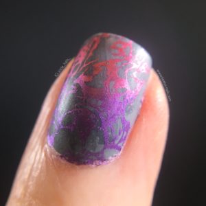 Left hand index finger macro photo, pointing to top right of photo, on a black background with grey, purple and pink nail art design