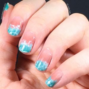 Left hand fingers curled gently into palm, on a black background. Nails with a pale pink gradient and a turquoise waves design at the tips.