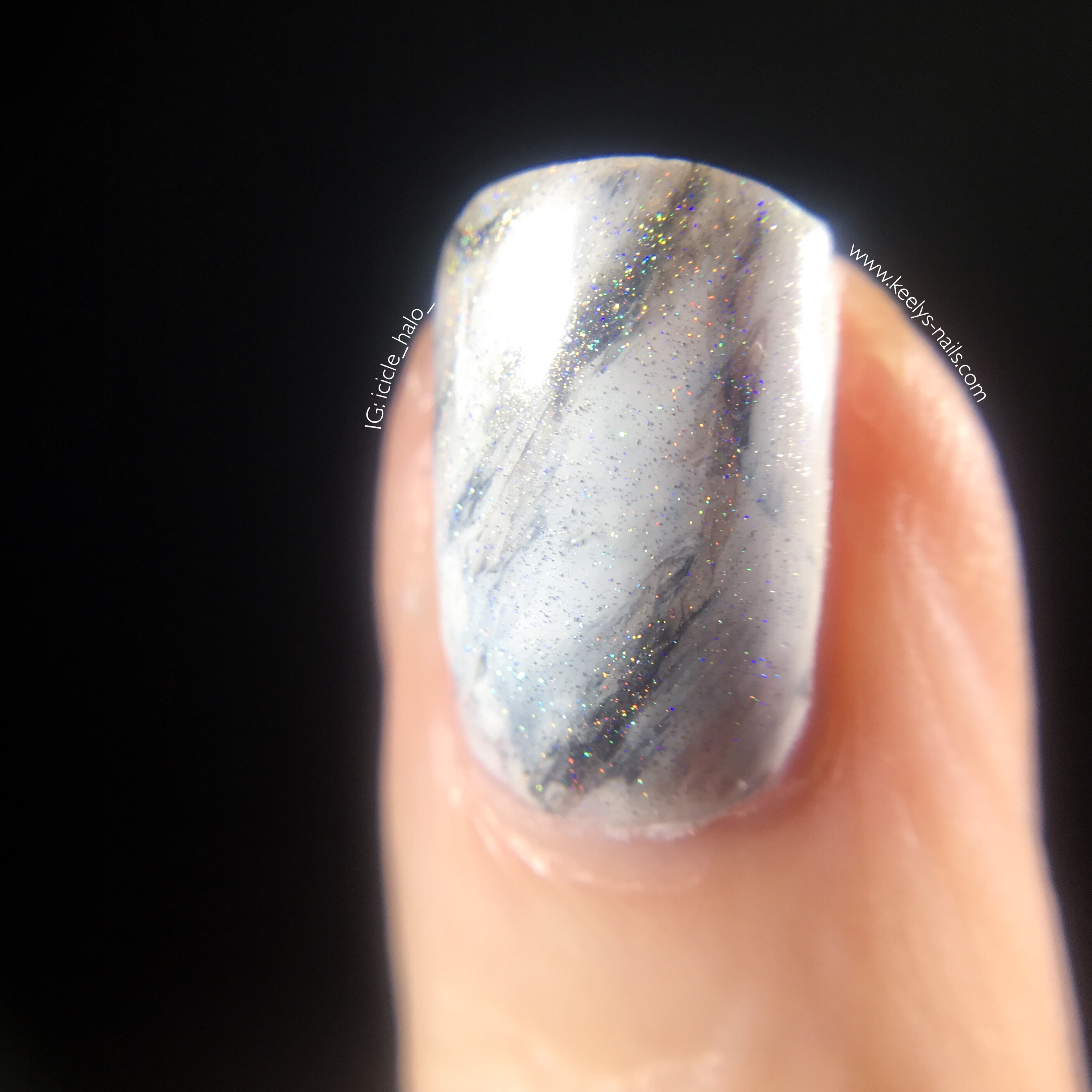 Close up of left hand ring finger nail with white marble nail art, showing the rainbow flecks of holographic top coat
